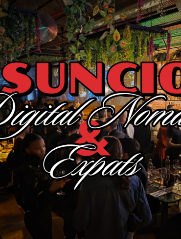 An image of a bustling pub with digital nomads and expats gathered at high-top tables in low lighting, engaged in conversation.